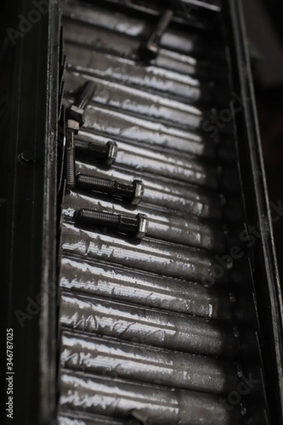 Fototapeta the raw material of the screw and machine producing bolts at the factory 