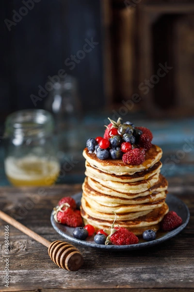 Fototapeta Pancakes with berries and maple syrup. Sweet homemade stack of pancakes