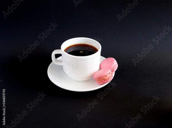 Fototapeta A Cup of black coffee and macaroons on a black background. Suitable for mockups and advertising backgrounds