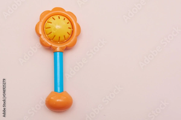 Fototapeta Plastic toy rattle in bright yellow color with a blue handle. Plastic Retro Rattle. Baby toys on pink background. Flat lay. Copy space.