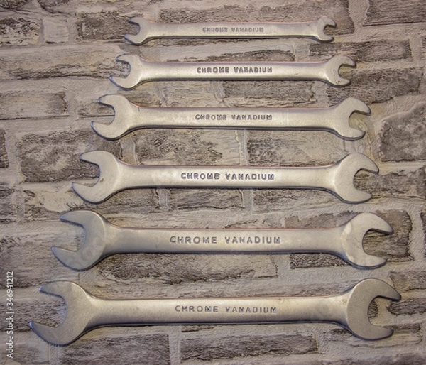 Fototapeta Set of open-end wrenches under the nuts on a brick wall background. .