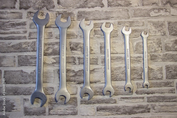 Fototapeta Set of open-end wrenches under the nuts on a brick wall background. .