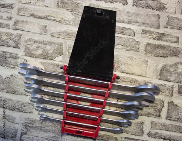 Fototapeta Set of open-end wrenches under the nuts on a brick wall background. .