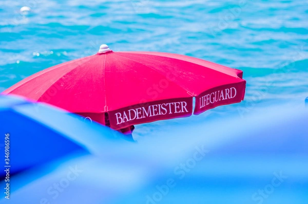 Obraz red umbrella and lifeguard chairs for your safety at the sea