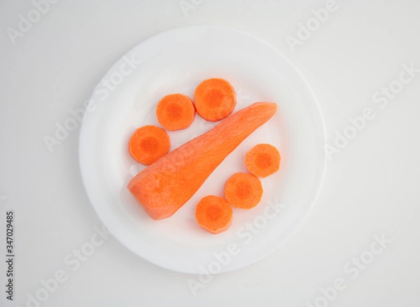 Obraz fresh peeled carrots and sliced carrot slices on a white plate white isolated background
