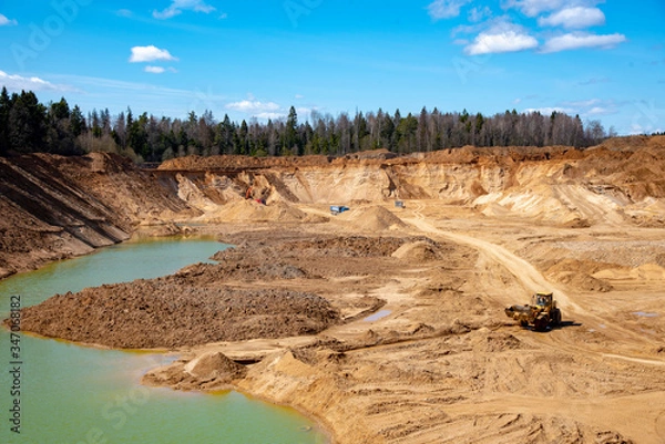 Fototapeta Sand deep quarry under a blue cloudy sky.