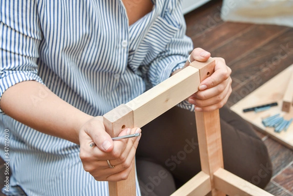 Fototapeta woman hands assembling wooden furniture with tools during quarantine isolation.