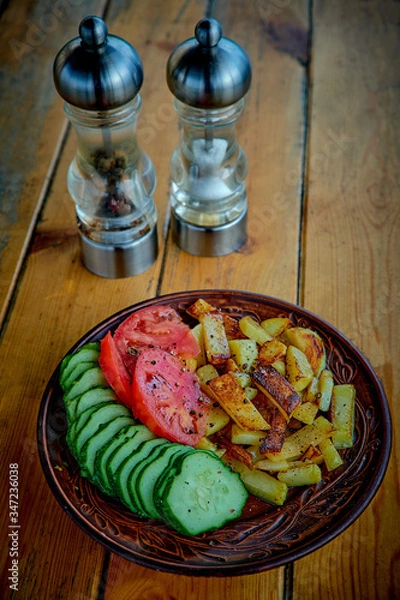 Fototapeta Potatoes, cucumbers and tomatoes on a wooden table.