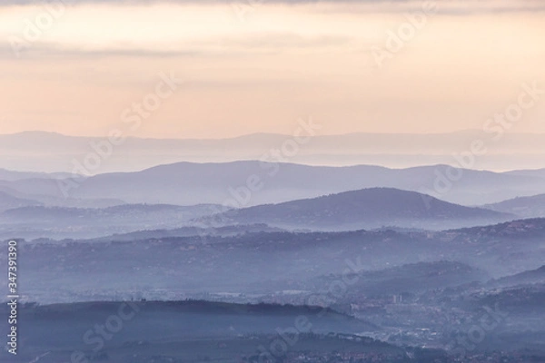 Fototapeta Sea of fog and mist between layers of mountains and hills at dusk
