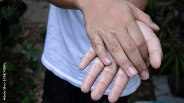 Fototapeta A boy in a white shirt is cleaning both hands with alcohol gel. To prevent the spread of the covid-19 virus..