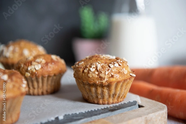 Fototapeta Fresh homemade delicious carrot muffins decorated with oat flakes and brown sugar on rustic table