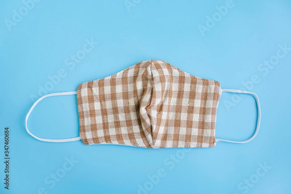 Fototapeta Handmade cotton face mask protective pollution, dust, or virus spread on color background. Coronavirus (COVID-19) preventive cotton mask, homemade face mask by fabric DIY concept. Top view, copy space