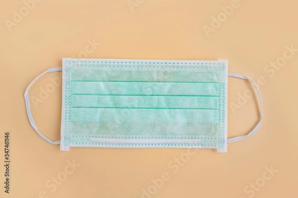 Fototapeta Medical mask isolated on color background. Green medical face mask protection against pollution, virus, flu, and coronavirus. Disposable surgical face mask cover mouth and nose. Health care concept.