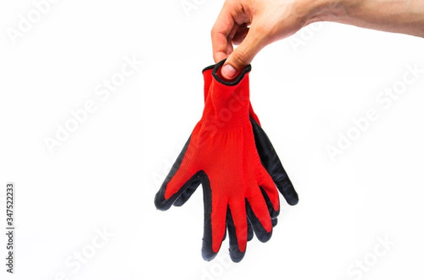 Fototapeta Gloves for workers, construction red with black rubber coating. Black-red gloves. Hand holds, throws out gloves on a white background. Used  gloves