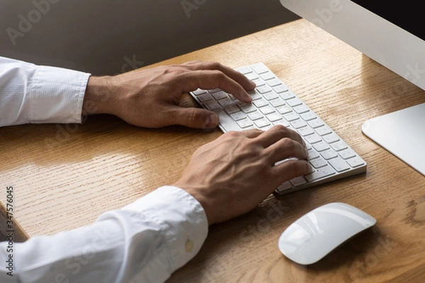 Fototapeta Men's hands, keyboard and mouse on the wooden table