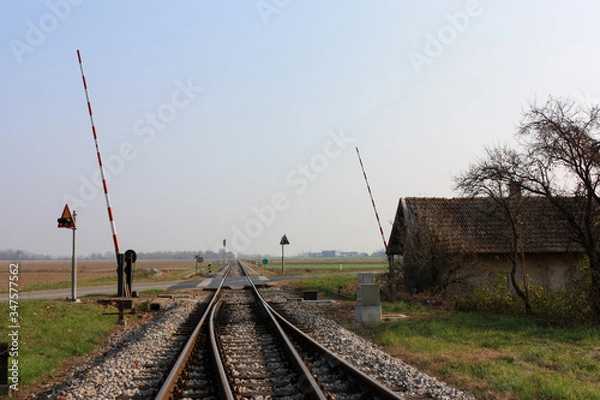 Fototapeta Railway to horizon perspective with opened barriers. Autumn. Blue sky.