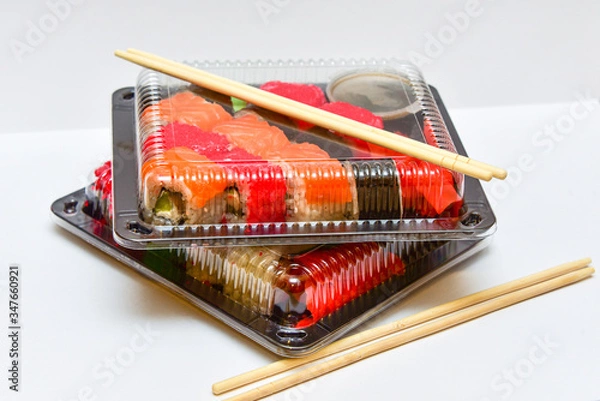Fototapeta Sushi rolls pack in plastic container on white background