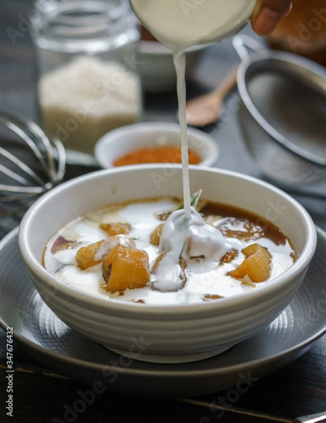 Fototapeta Pour coconut milk on the banana compote.