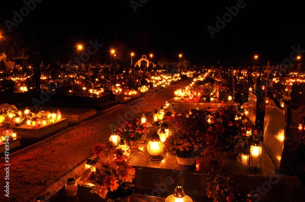 Fototapeta Candle flames illuminating on cemetery during All Saint's Day
