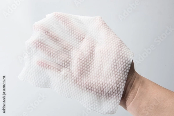 Fototapeta A paper towel is held in one hand for thickness testing against a white background.