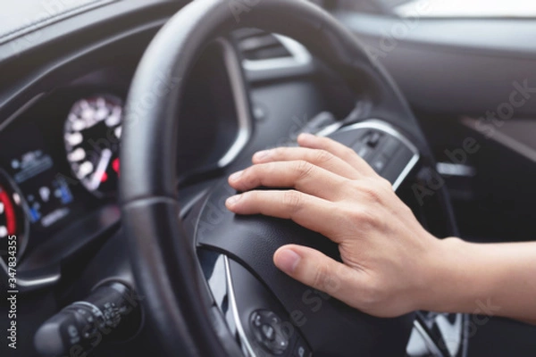 Fototapeta man pushing horn while driving sitting of a steering wheel press car, honking sound to warn other people in traffic concept.