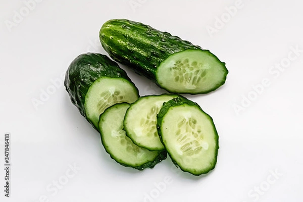 Fototapeta green cucumber cut into pieces on a white background macro shot