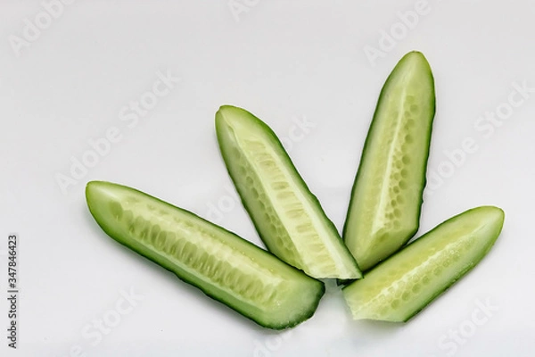 Fototapeta green cucumber cut into pieces on a white background macro shot