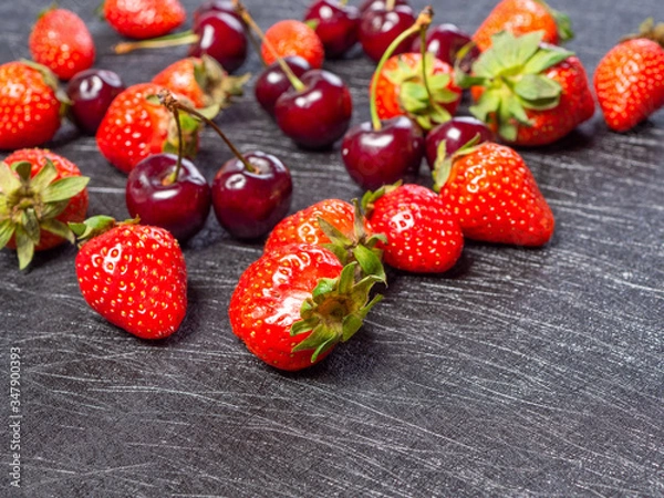 Fototapeta Fresh cherries and strawberries on a black background