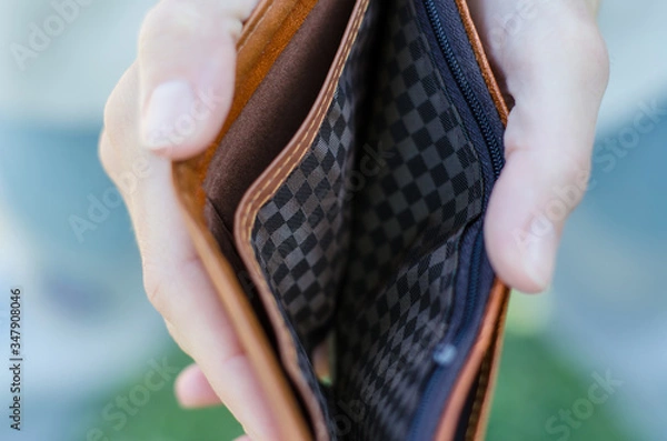 Fototapeta The girl holds an empty purse in her hands. Bankruptcy and crisis concept. A lack of money.