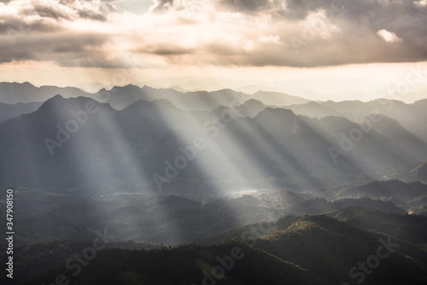 Fototapeta Golden light rays from clouds shining down to mountains. Sun rays over valley. Sun rays over hill. Beam of light from clouds on the mountains. Heaven in nature. Mon Pui Mok, Mae Moei, Tak, Thailand.
