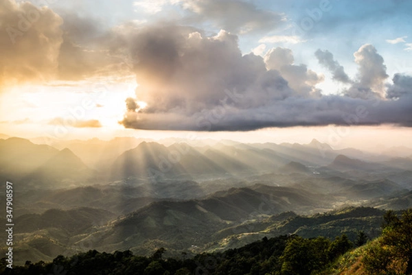 Fototapeta Golden light rays from clouds shining down to mountains. Sun rays over valley. Sun rays over hill. Beam of light from clouds on the mountains. Heaven in nature. Mon Pui Mok, Mae Moei, Tak, Thailand.