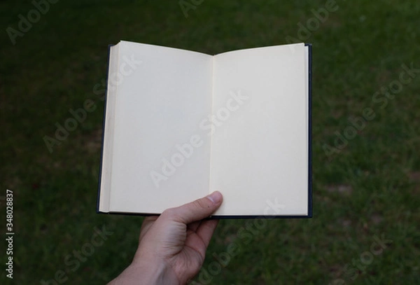 Obraz White open notebook held by hand. POV.