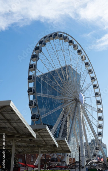 Fototapeta A white wheel of fortune in front of the blue sky with a few clouds