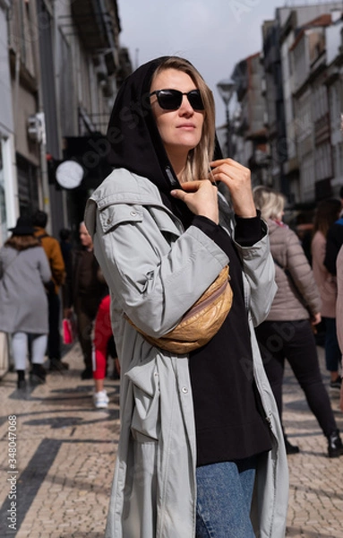 Obraz A stylish woman in a trench coat stands on a busy street