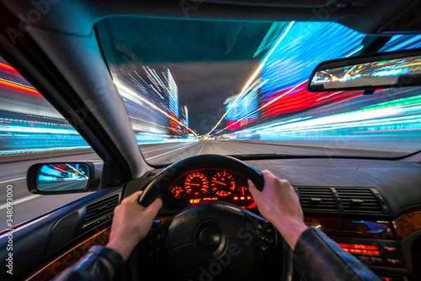 Obraz Movement of the car at night at high speed view from the interior with driver hands on wheel. Concept spped of life.