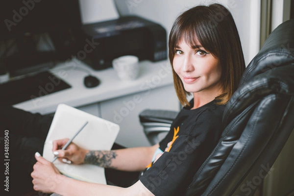 Obraz Young woman study and taking notes in notebook in her home office. Remote worker. Work from home. Education online.