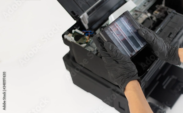 Fototapeta Printer repairman holding continuous ink system tanks. Copy space. Concept of professional printer maintenance Technical assistance in office hardware Continuous repair of the ink system.