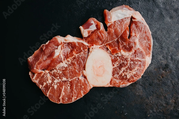 Fototapeta Raw beef steak osso bucco with herbs and spices on dark table. Marble meat. Top view and copy space