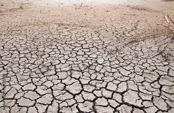 Fototapeta Dried clay soil with large cracks in hot weather. The dried bottom of a reservoir.
