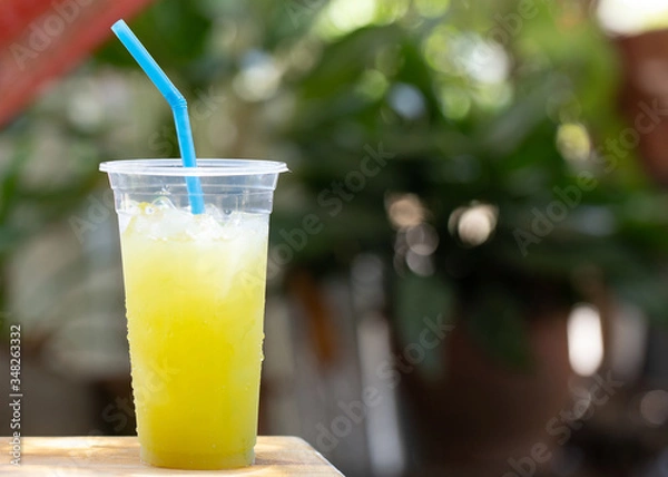 Fototapeta Ready to drink sugarcane juice in plastic glasses on the wooden floor there is a bokeh backdrop.