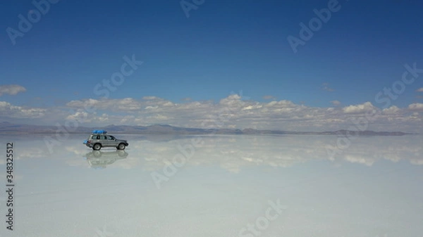 Fototapeta Car in Salar de Uyuni, Salt desert in Bolivia, seen with drone and Andes in the background