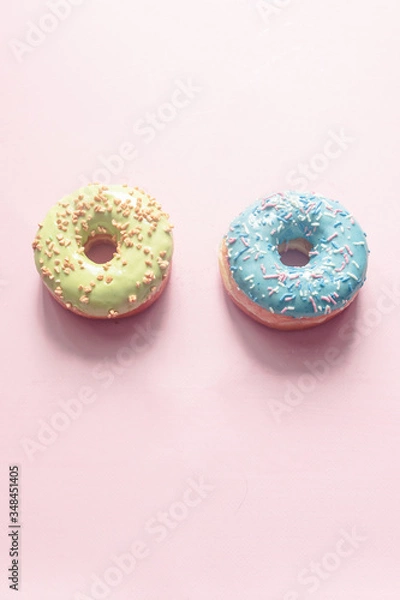 Fototapeta assorted donuts of different colors such as bubblegum, pistachio, bilberry and strawberry with frosted and filled with fruit jam and cream, colored glazed and sprinkled donuts on pink background