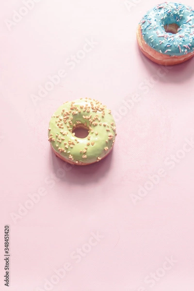 Fototapeta assorted donuts of different flavors as bubblegum, bilberry and strawberry with frosted and filled with fruit jam and cream, colored glazed and sprinkled donuts on pink background, pistachio