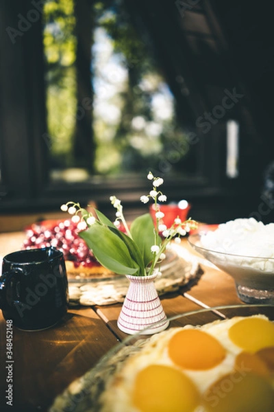 Fototapeta Nahaufnahme von Maiglöckchen in einer Vase auf einem gedeckten Kaffee Tisch