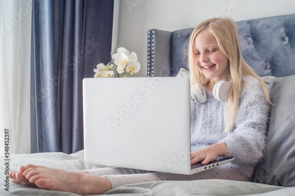Fototapeta Pre teen girl playing on tablet. Virtual class lesson on video during self isolation at home. Distant remote video education. Modern school study for kids.