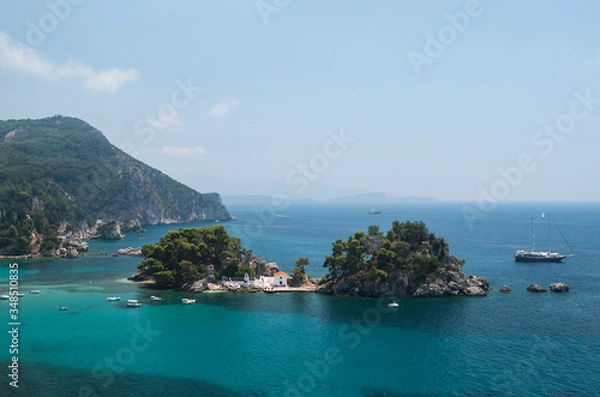 Fototapeta in the bay of Parga, an island and a chapel, boats are waiting on the blue Mediterranean sea,