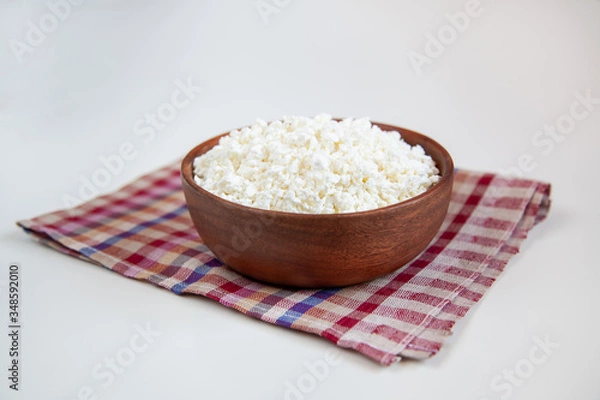 Obraz Wooden bowl with cottage cheese on the white table.