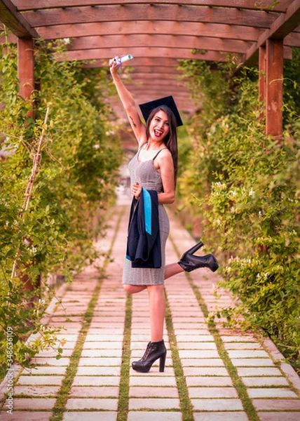 Obraz Woman taking a lot of different graduation photos in a beautiful botanical park.