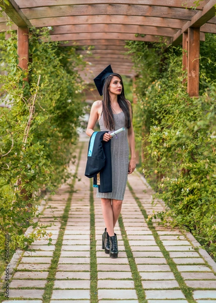 Obraz Woman taking a lot of different graduation photos in a beautiful botanical park.