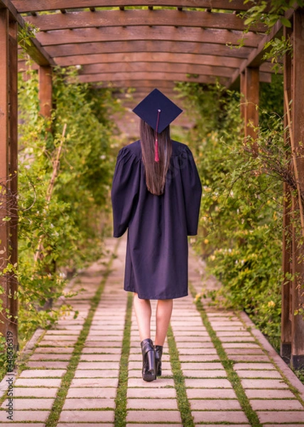 Obraz Woman taking a lot of different graduation photos in a beautiful botanical park.